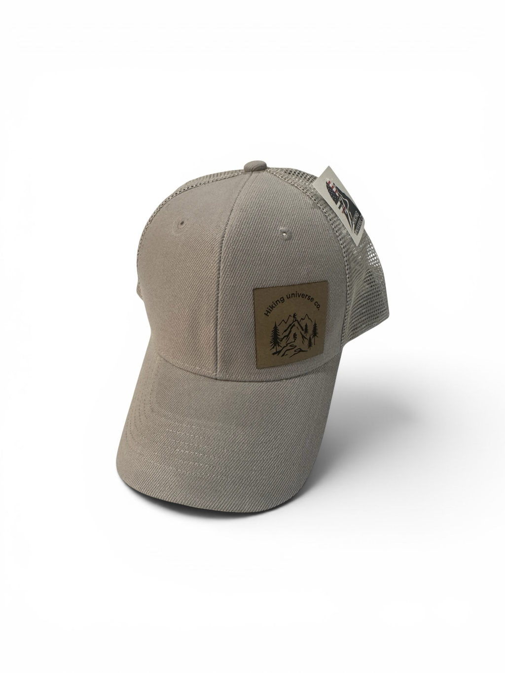Hiking Universe Co. beige cotton twill trucker hat with mesh back and faux leather mountain logo patch. Adjustable snapback.